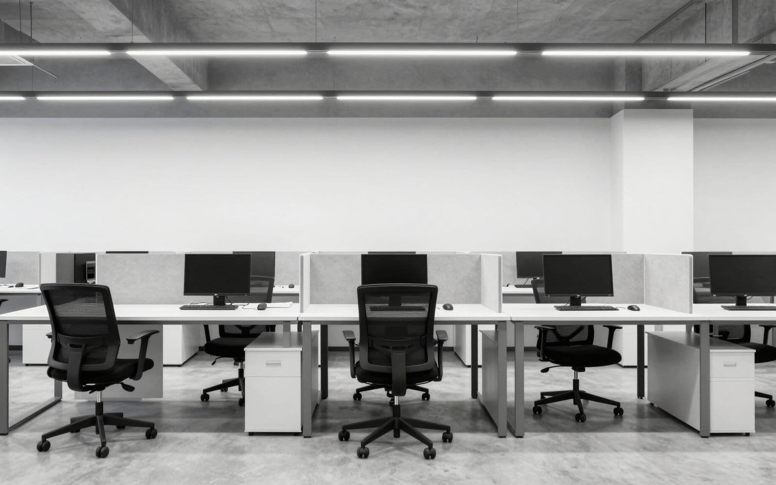 An empty open-plan office with rows of monitors.